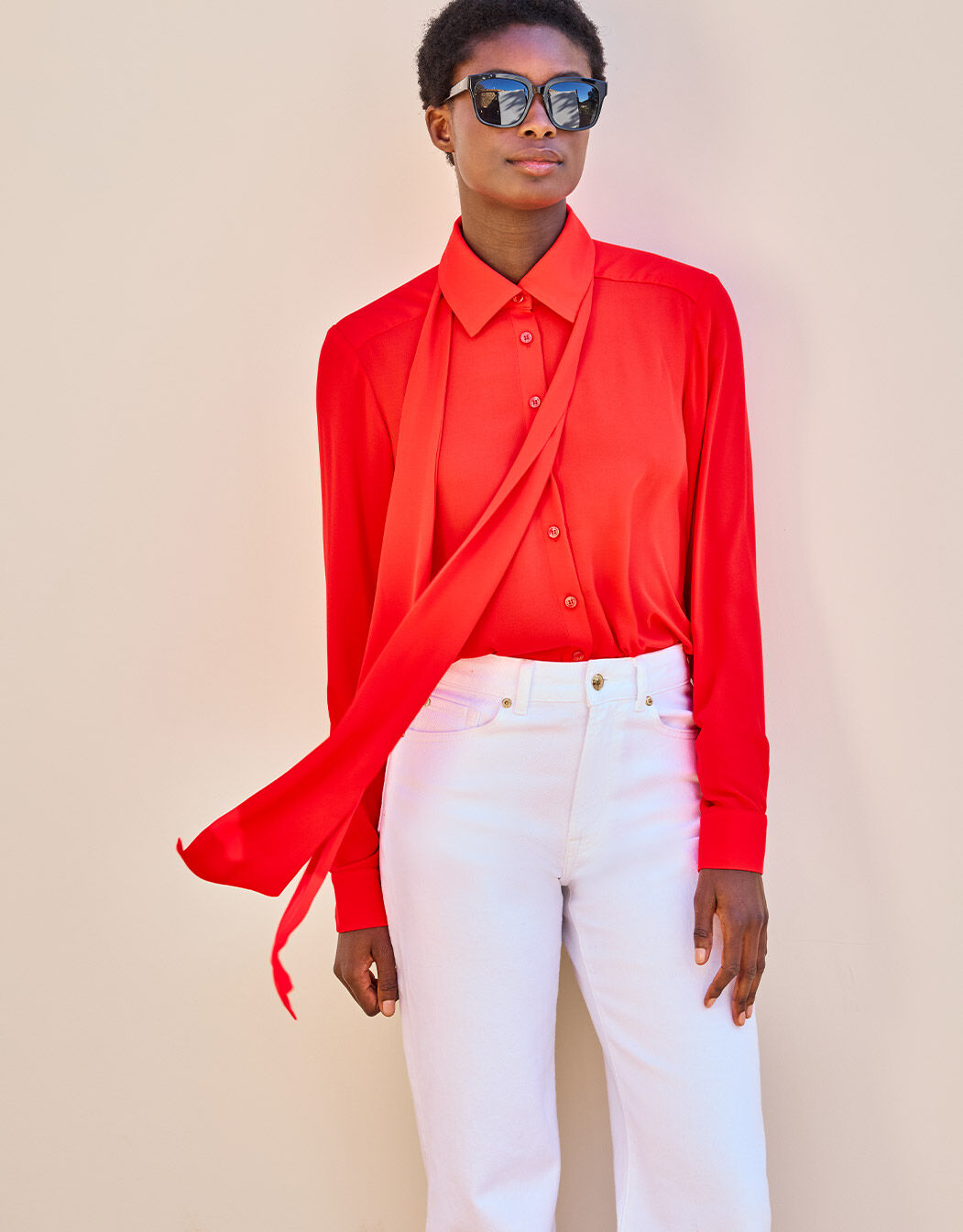 Model standing in the Kris Hibiscus blouse in crepe georgette with white jeans.