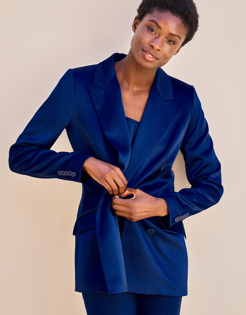Model standing in the Juliette Sapphire Blue Satin blazer in crepe satin with satin lapels.