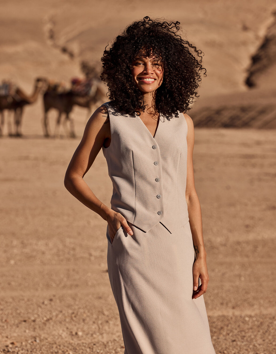 Model standing in the Charlize Pebble waistcoat in crepe satin with matching trousers in a desert.