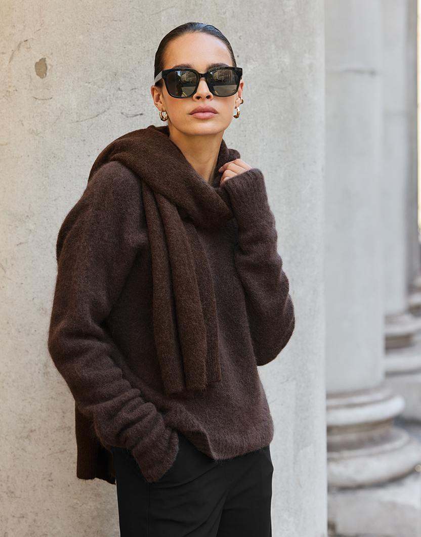 Model steht im Zora Espresso Pullover aus Alpaka-Mischung mit einem passenden Schal.