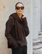 Model steht im Zora Espresso Pullover aus Alpaka-Mischung mit einem passenden Schal.