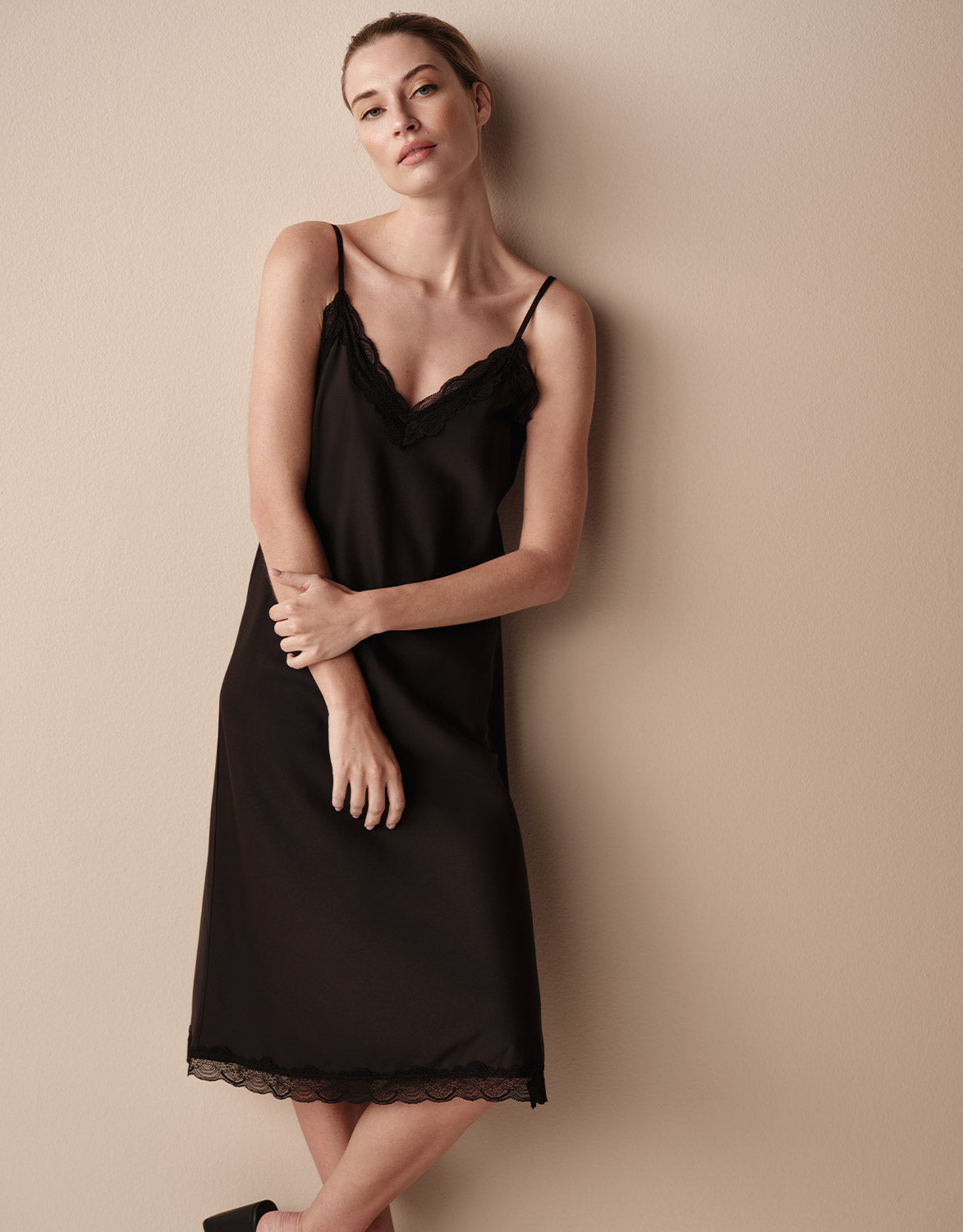 Model wearing the Aurora Black slip dress with thin straps and a lace hem.