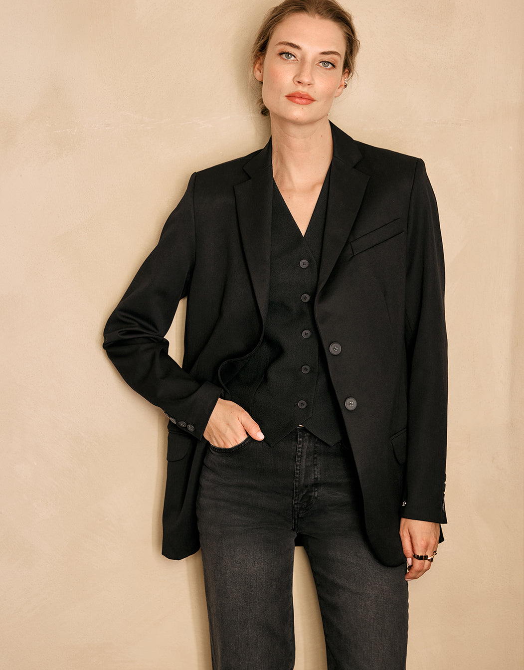 Model wearing the Beau Black blazer over a black waistcoat and grey jeans.