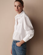 Model standing in the Cathy White blouse in poplin, tucked into blue jeans.