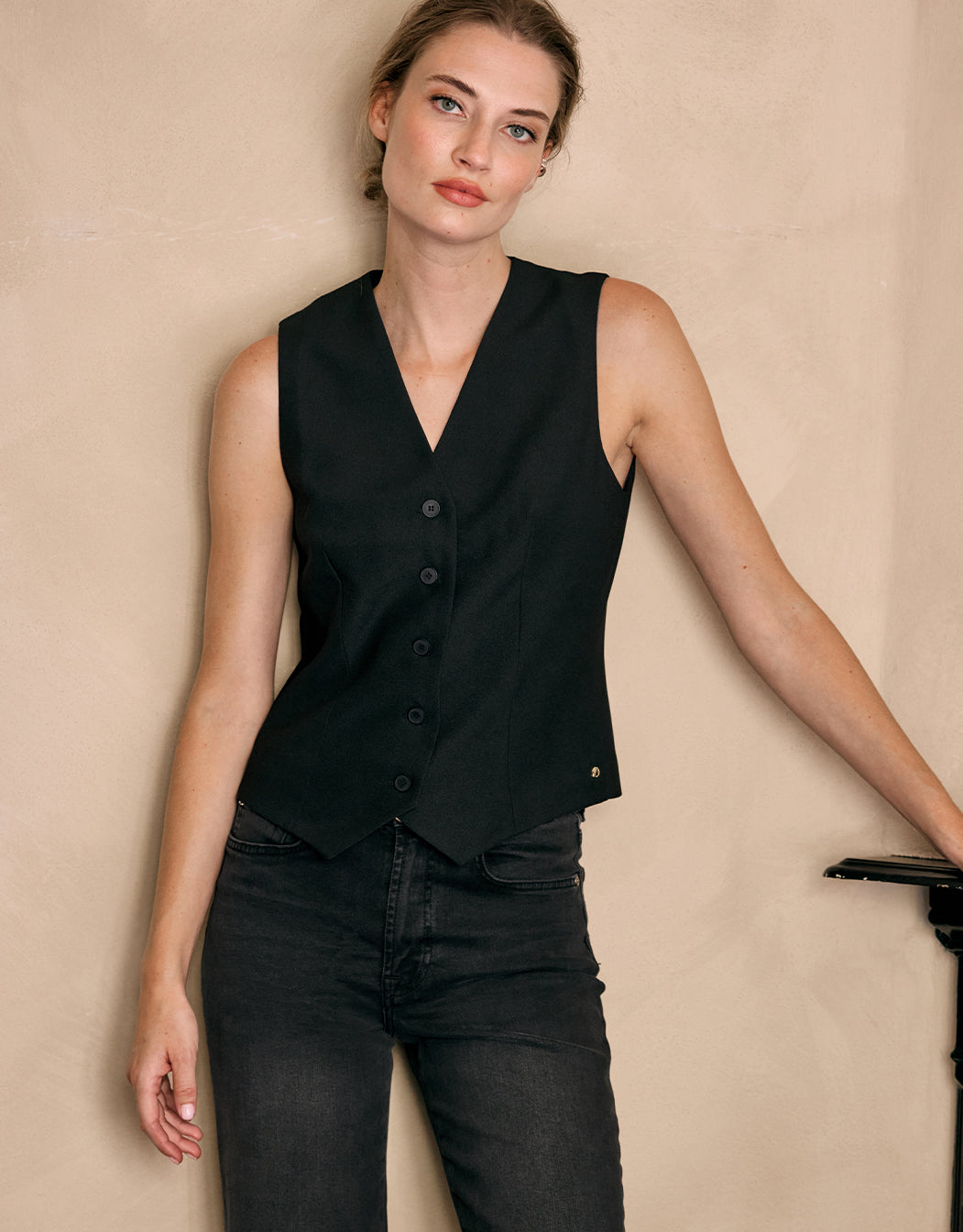 Model standing in the Charlize Black waistcoat in crepe satin, worn with dark jeans.