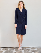 Model steht im Colette Midnight Blue Kleid aus Crêpe-Satin mit Gürtel und weißen Sandalen.