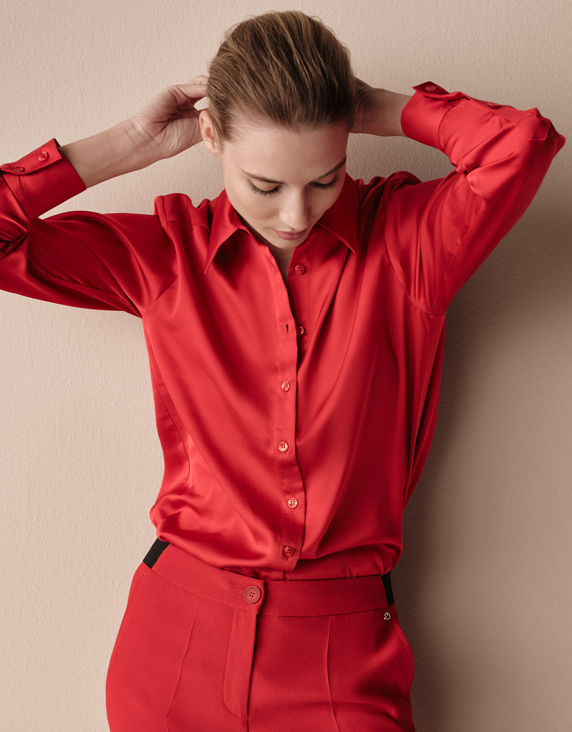 Model standing in the Estee Raspberry Red blouse in satin with matching red trousers.