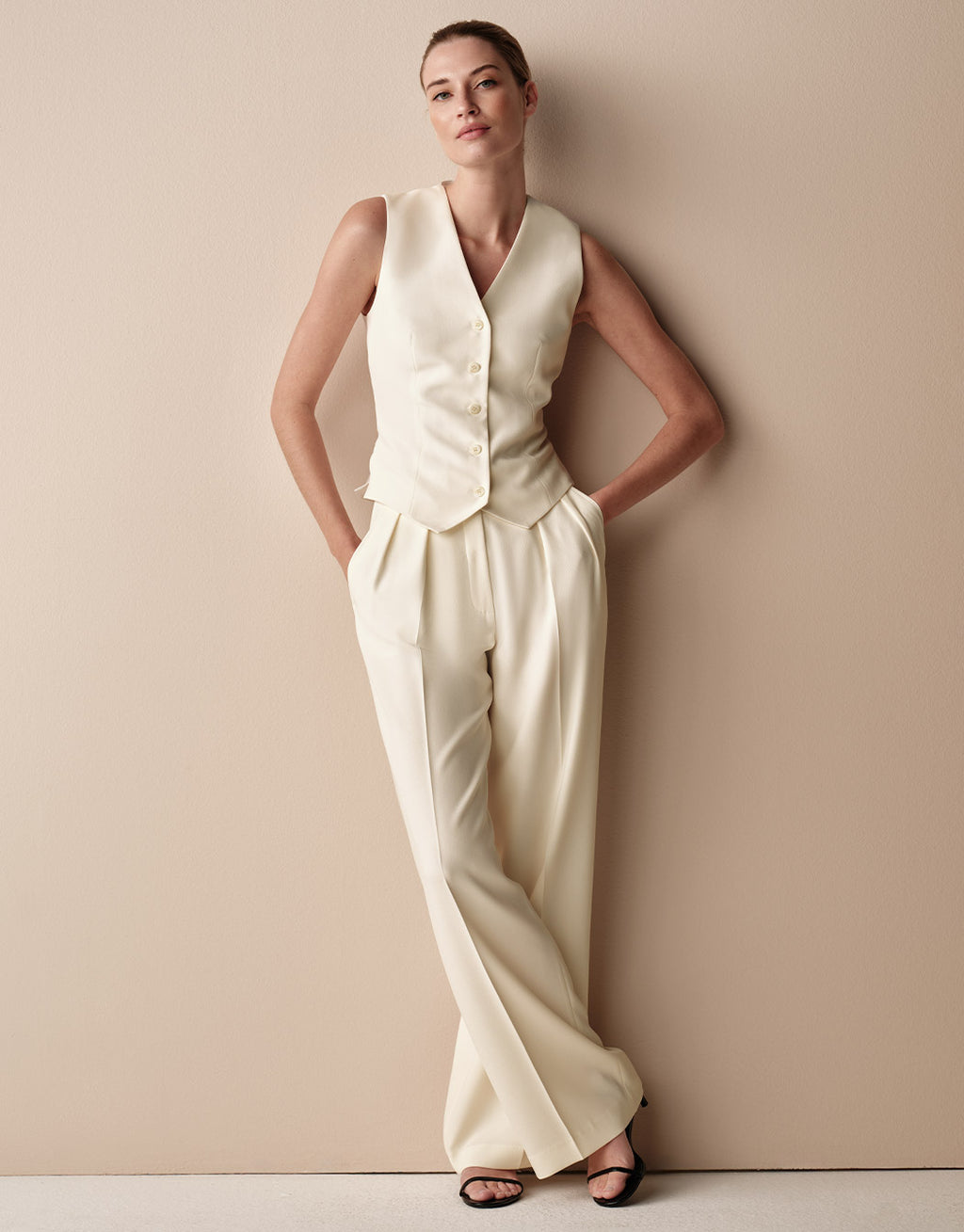 Model standing in the Toledo Ivory trousers in crepe satin with a matching waistcoat.
