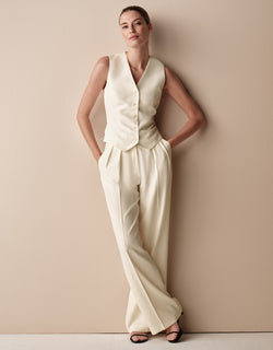 Model standing in the Toledo Ivory trousers in crepe satin with a matching waistcoat.