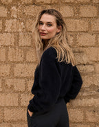 Model standing in the Leonora Black cardigan in alpaca blend, seen from the side.