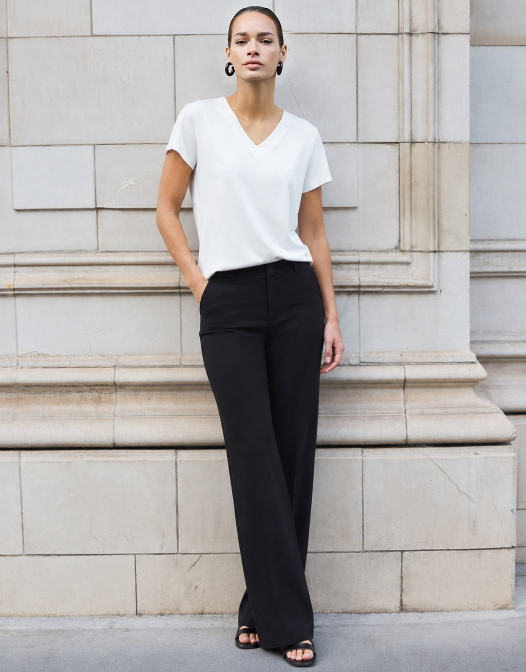 Model standing in the Liz White top in jersey lycra with wide black trousers.