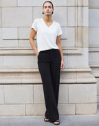 Model standing in the Liz White top in jersey lycra with wide black trousers.