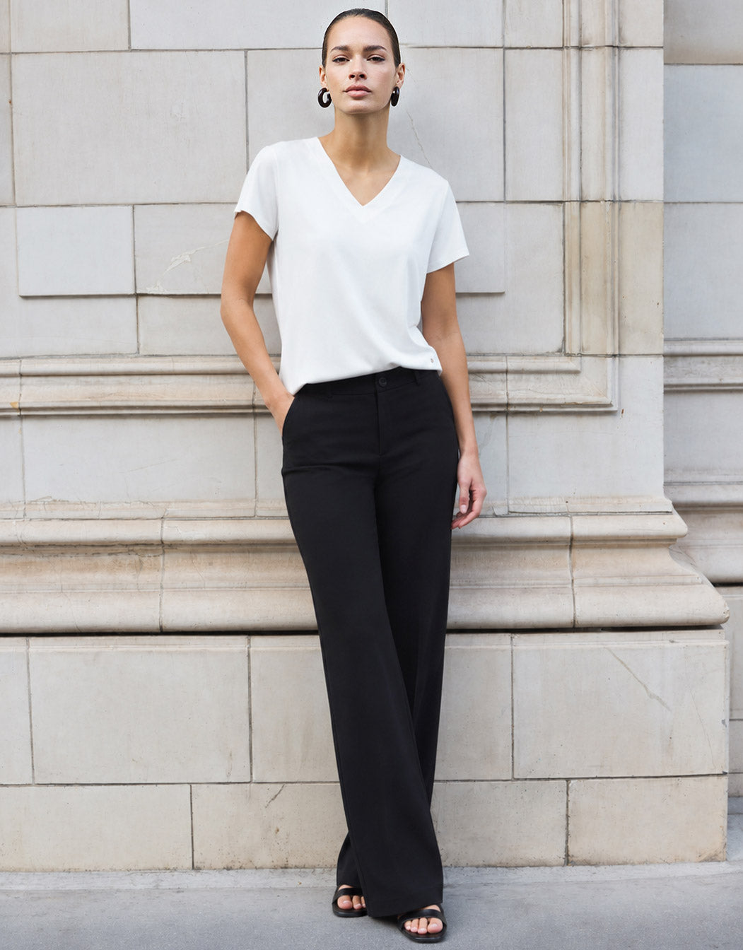 Model standing in the Liz White top in jersey lycra with wide black trousers.