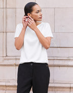 Model standing in the Liz White top in jersey lycra, tucked into black trousers.
