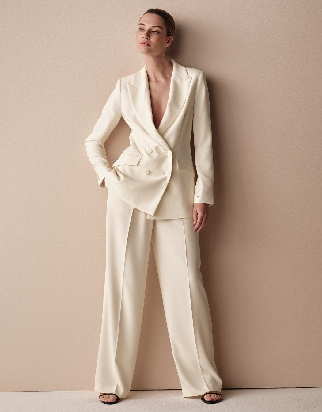 Model standing in the Toledo Ivory trousers in crepe satin with a matching blazer.