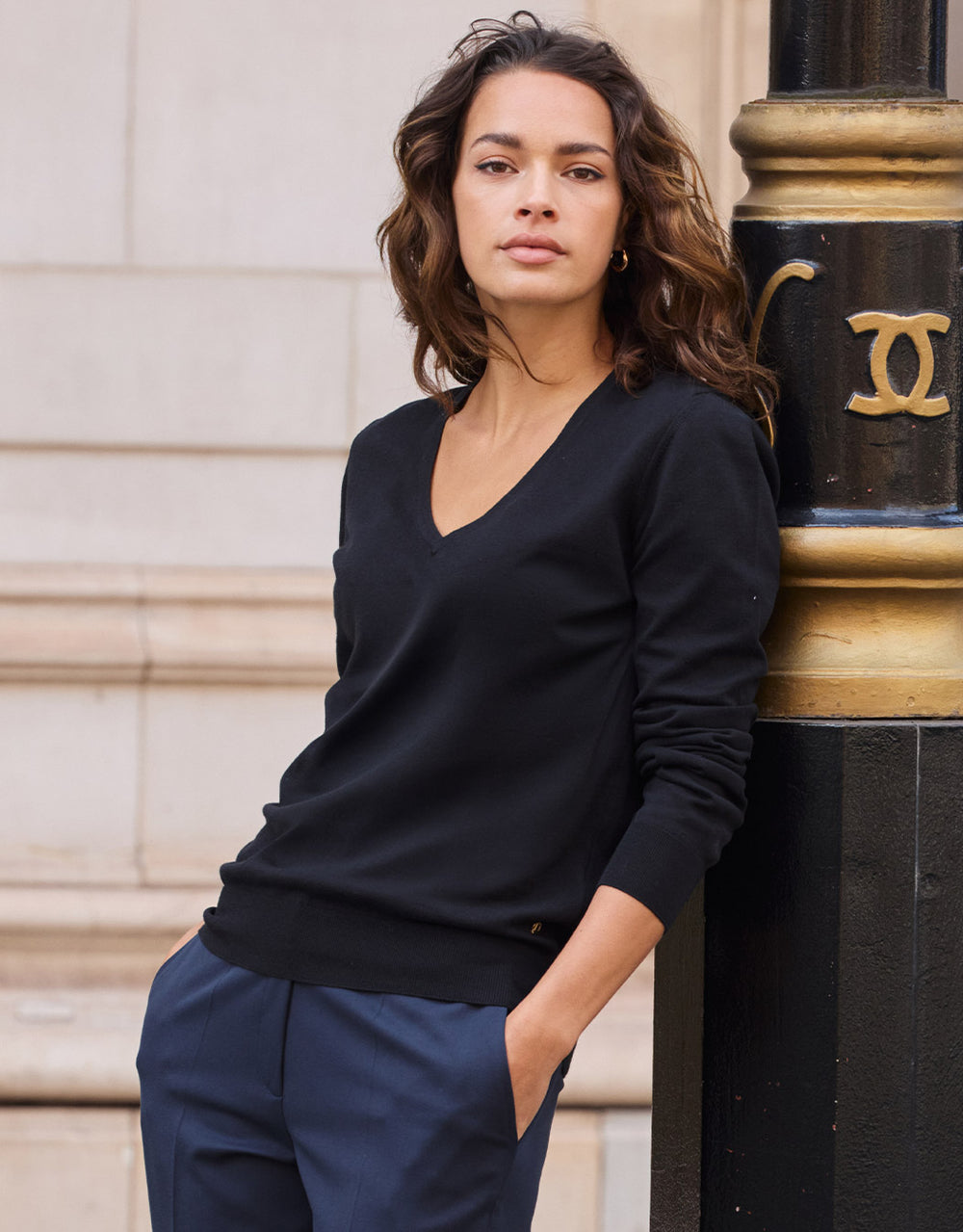 Model standing in the Loretta Black jumper in organic cotton knit with a V-neck.