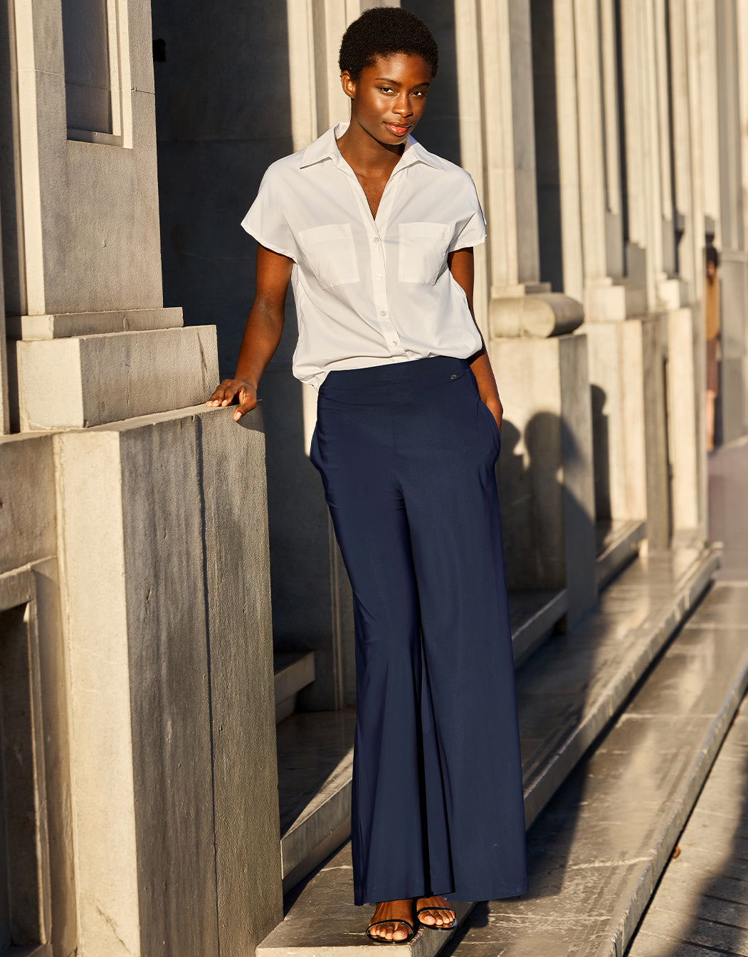Model standing in the Savona Midnight Blue trousers in jersey lycra with a white blouse.