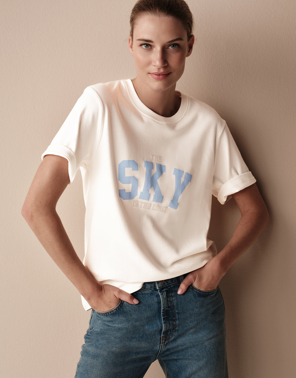 Model standing in the Story Tee Off White Sky in stretch cotton with a print with the text SKY.