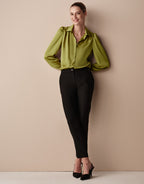 Model standing in the Tilda Lime blouse in satin with black tapered trousers.