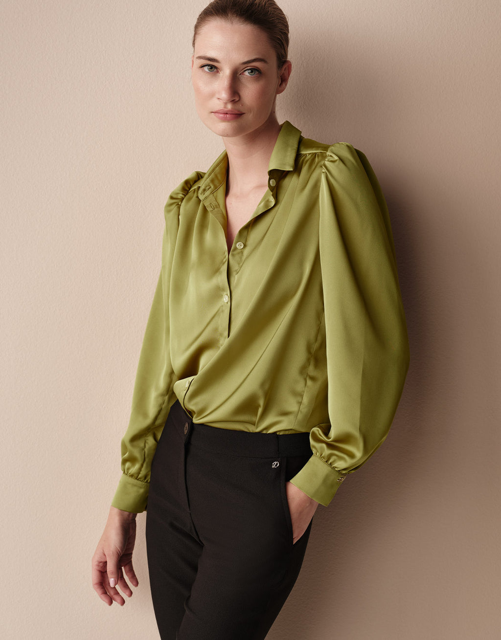Model standing in the Tilda Lime blouse in satin with black trousers.