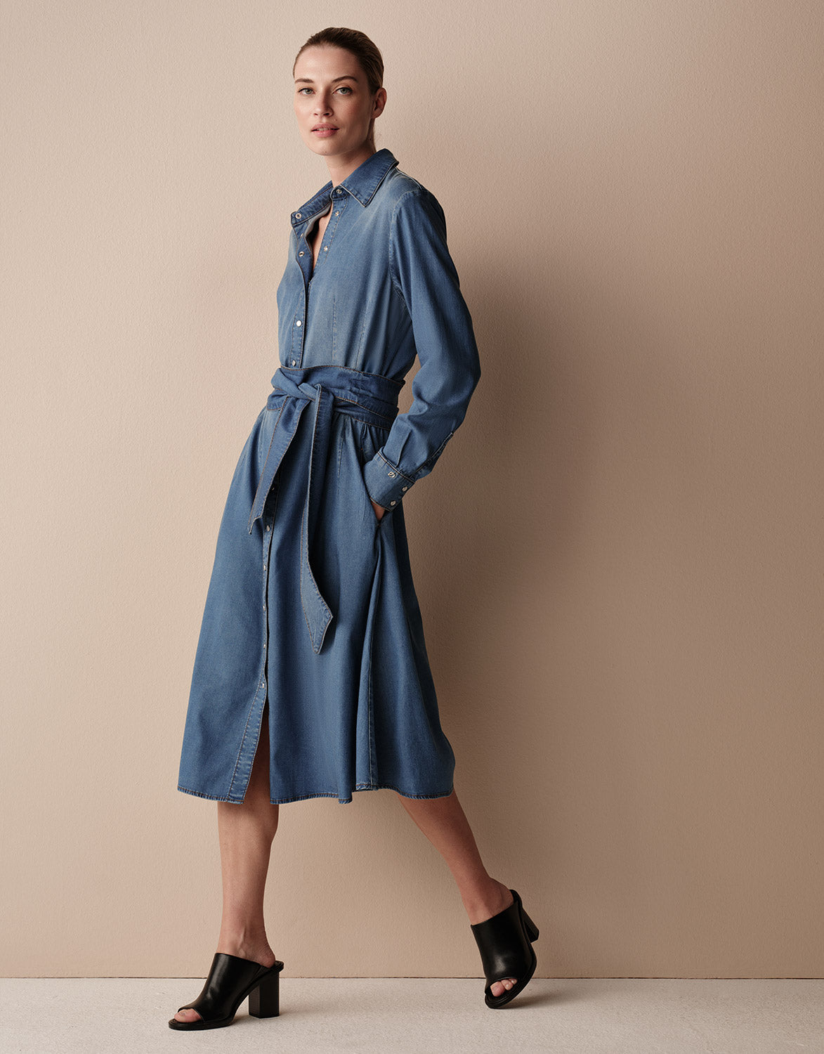 Model standing in the Zarah Blue Indigo dress in stretch lyocell denim with mules.