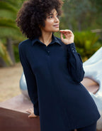Woman poses outdoors in an elegant dark blue blouse with long sleeves and a classic collar, suitable for the office or casual outings.