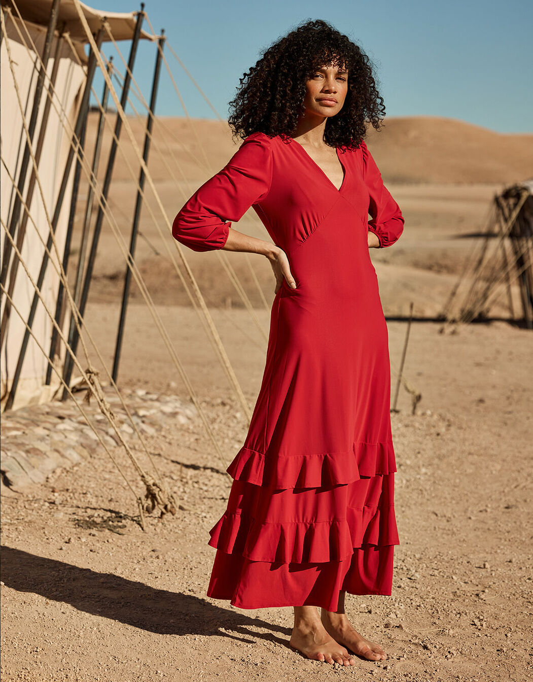 Model standing in the Sia Raspberry Red dress in jersey lycra with a tiered ruffled hem.
