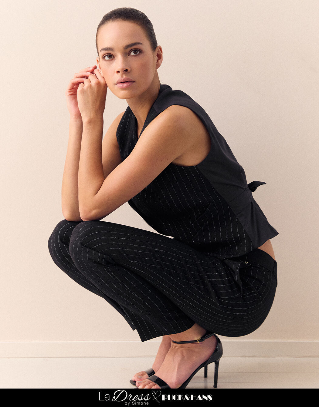 Model crouching in the Istanbul Black waistcoat in stretch woven with pinstripes.