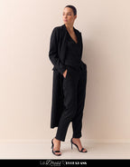 Woman wears elegant black pinstripe trousers with a matching blazer, a perfect business outfit in a modern style.