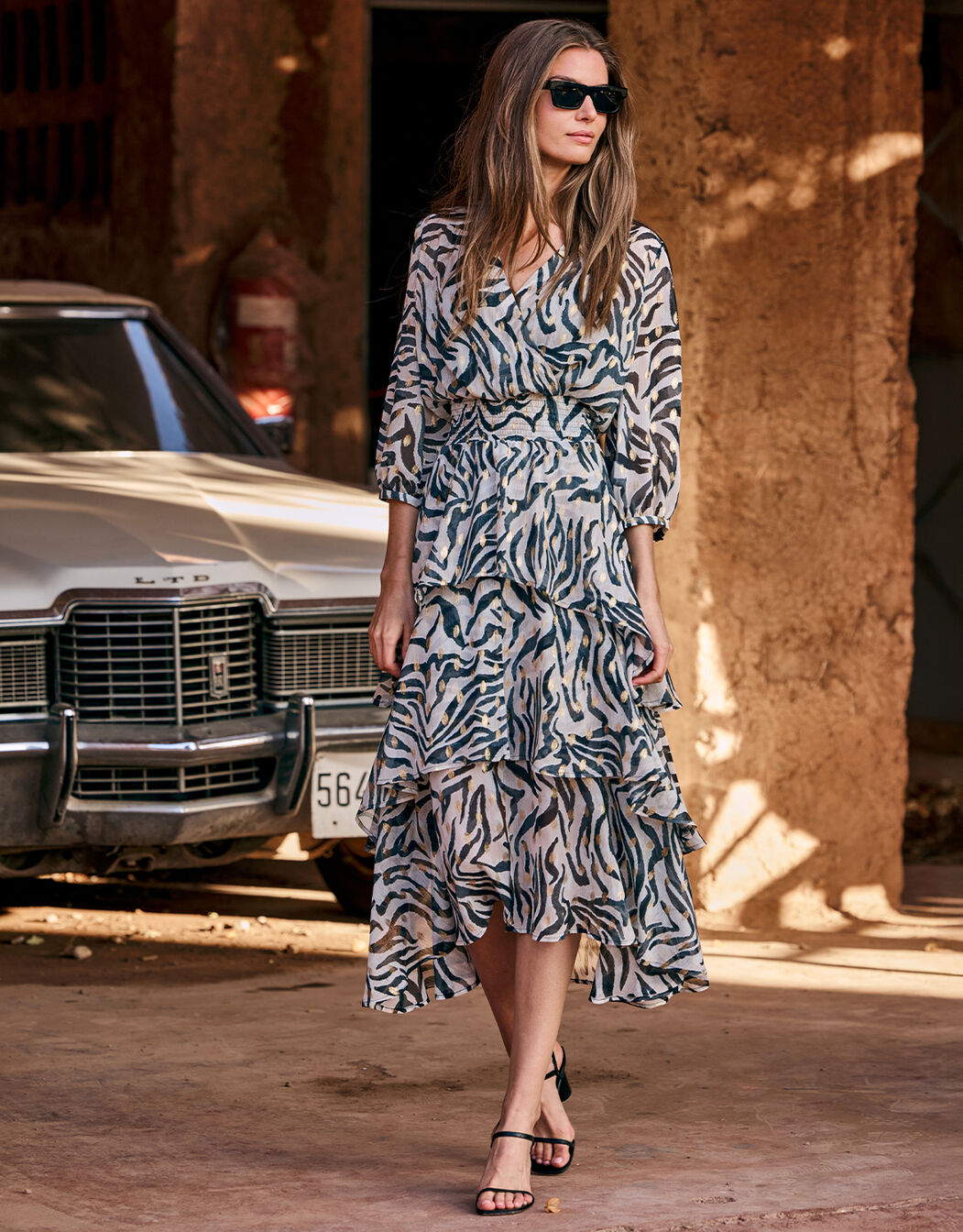 Model walking in the Mae Wild Stripes dress in chiffon with an animal print.