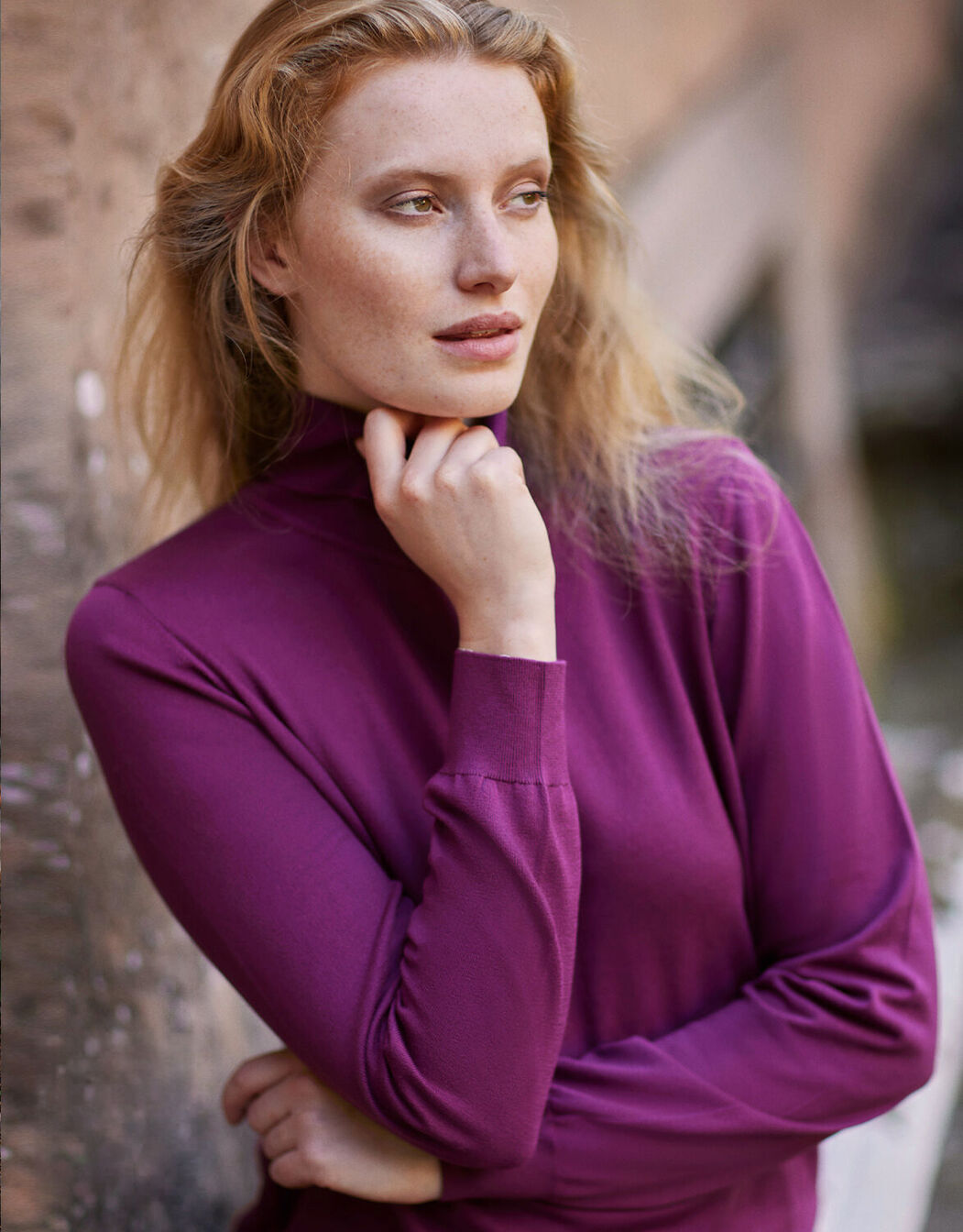 Model standing in the Jackie Mulberry jumper in organic certified cotton with a roll neck.
