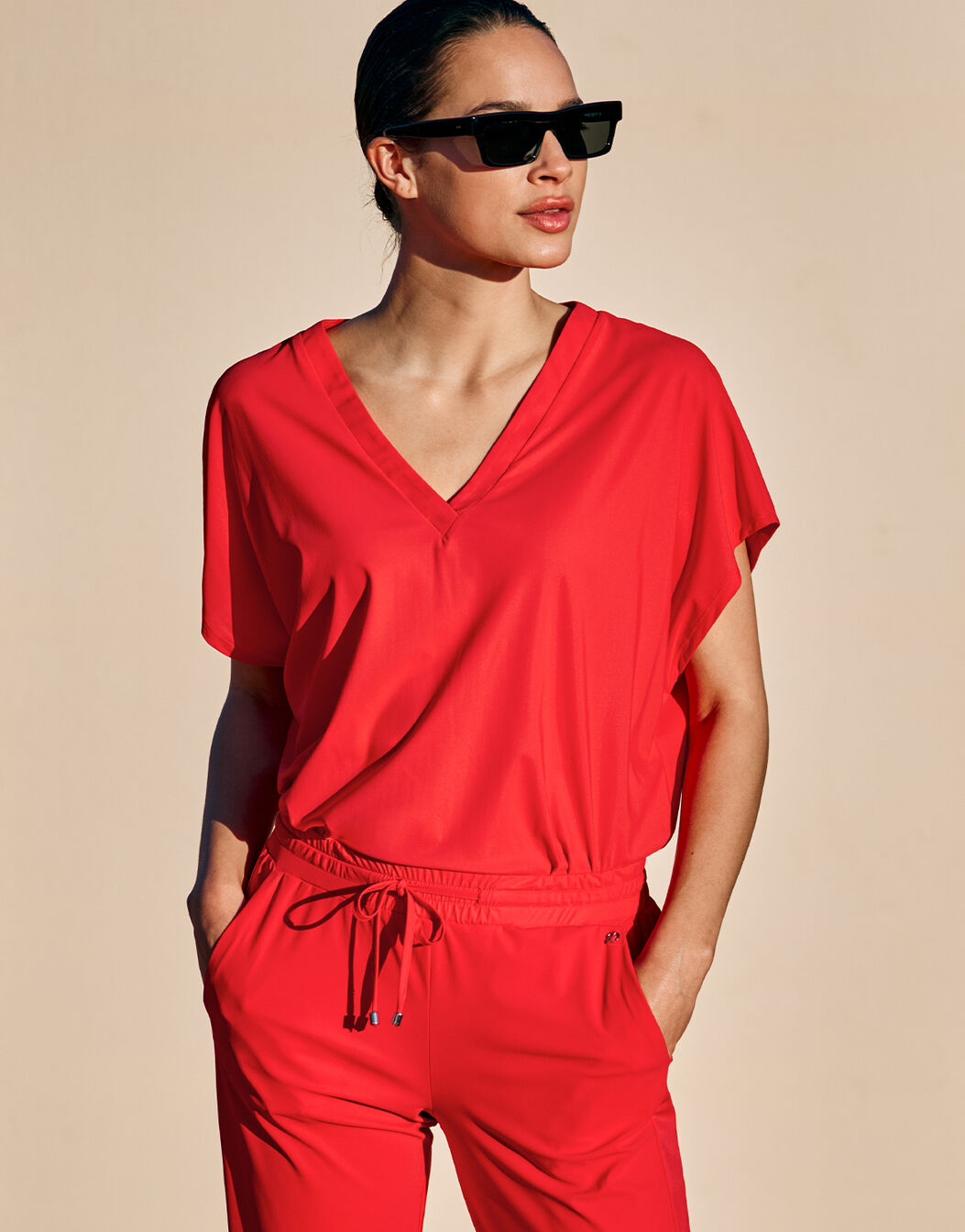 Model standing in the Liz Hibiscus top in jersey lycra with matching red trousers.