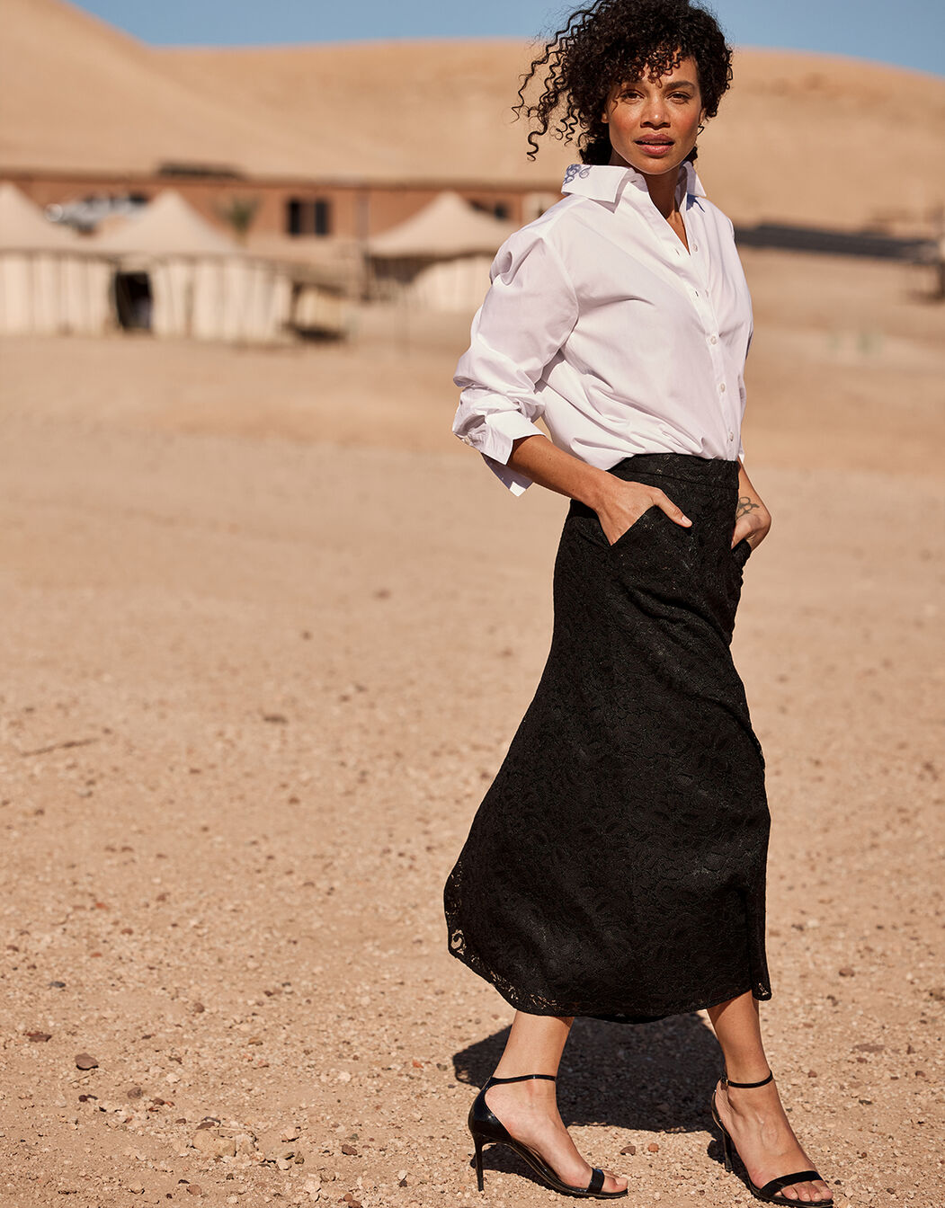 Model walking in the Vivienne Black skirt in lace with a white blouse.