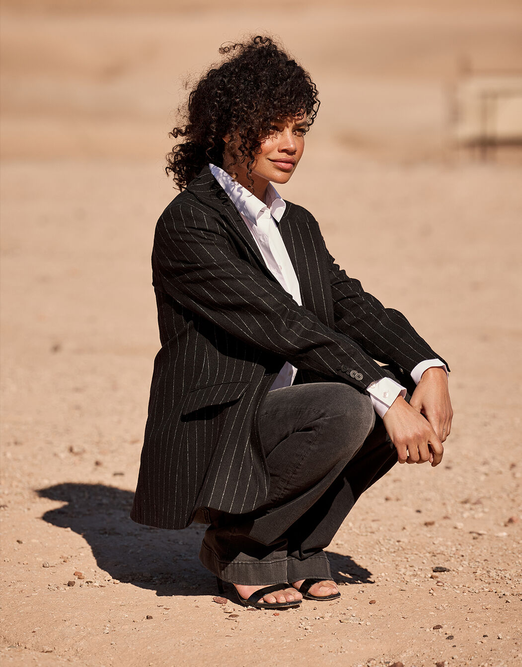 Model crouching in the Giorgia Black Stripe blazer in wool blend with a white shirt.