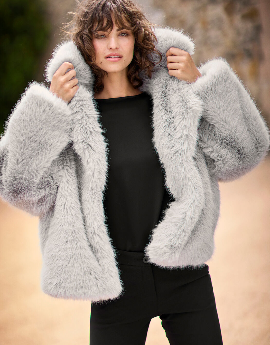 Model standing in the Lidia Silver coat in faux fur with a wide collar.