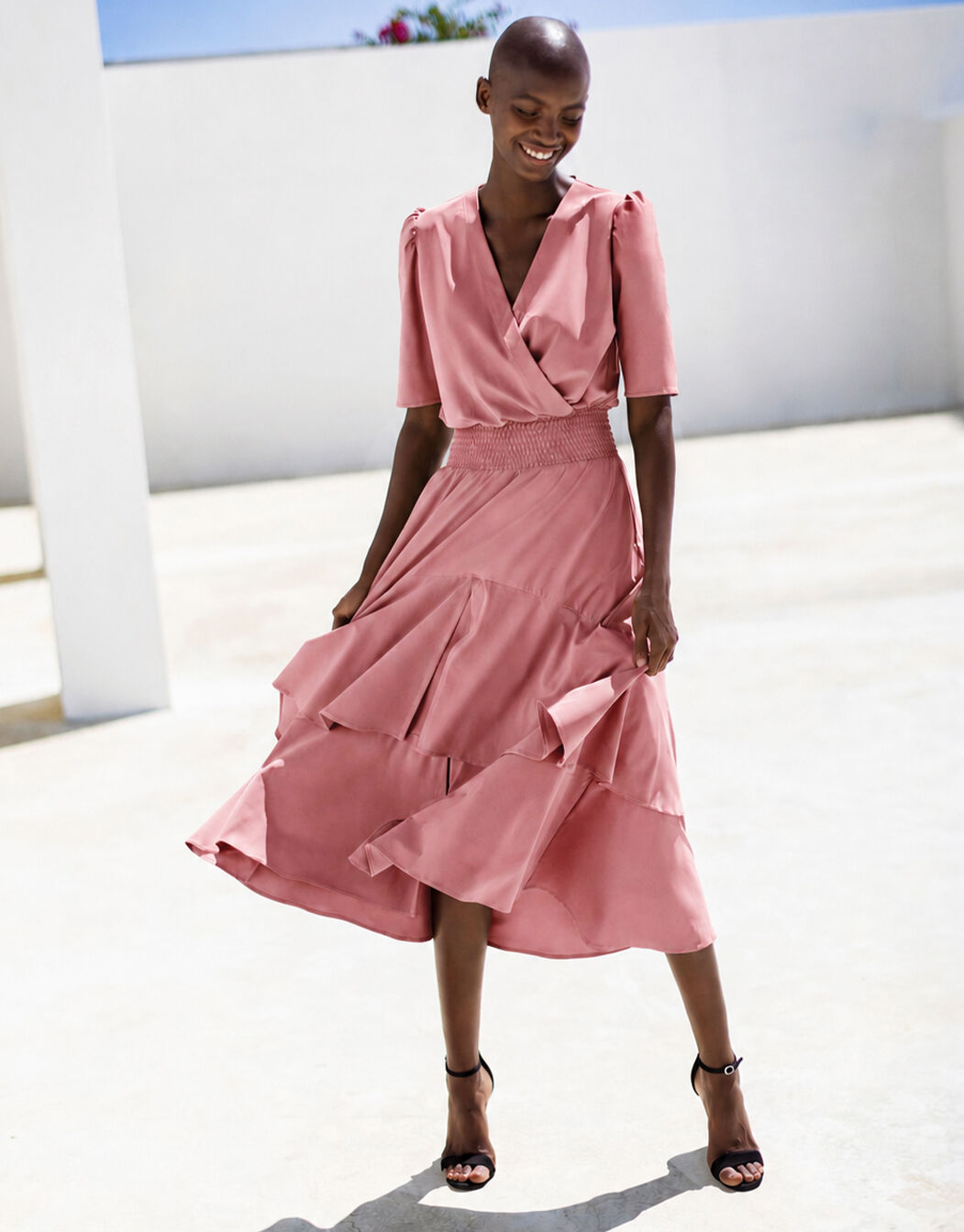 Model standing in the Lea Dusty Pink dress in jersey lycra with a tiered ruffled hem.