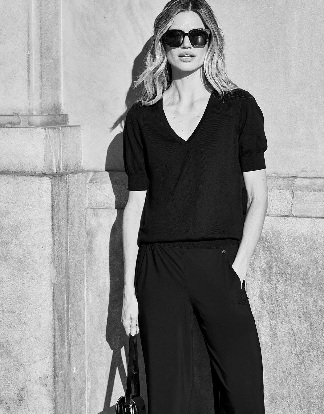 Model standing in the Marie Black jumper in organic cotton knit, in a black and white image.