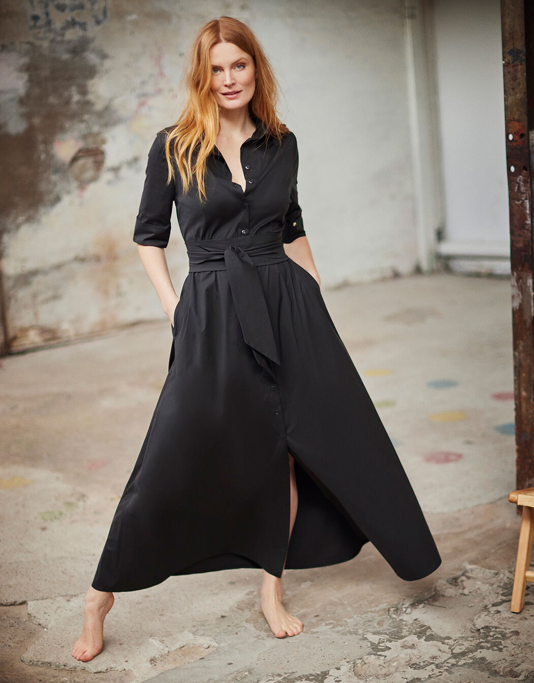 Model standing in the Yasmin Black dress in cotton stretch poplin with a tie belt.