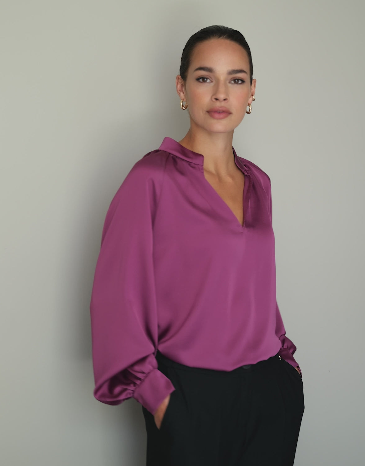 Video of a model wearing the Jolie Plum blouse in satin with black trousers.